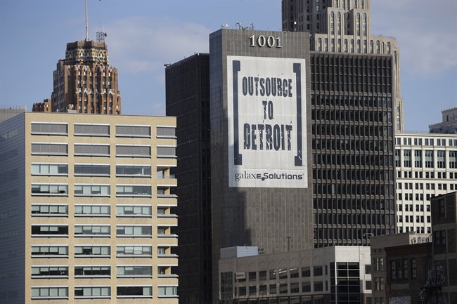 In this July 12, 2013, photo an Outsource to Detroit banner from GalaxE.Solutions is seen on a Detroit building.