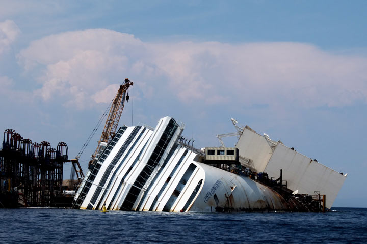 The wreckage of the Costa Concordia cruise ship lays aground over the rocks of Le Scole on July 7, 2013 off the Italian island of Isola del Giglio. A year on from the Costa Concordia tragedy in which 32 people lost their lives, the giant cruise ship still lies keeled over on an Italian island. The trial for manslaugher of the ship's captain Francesco Schettino opens on July 9, 2013. 