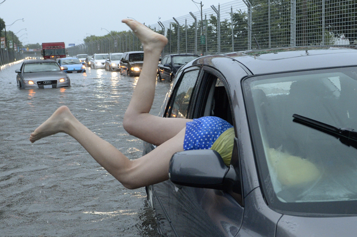 A woman gets gets back in her car in flood water on Lakeshore West during a storm in Toronto on Monday, July 8, 2013. THE CANADIAN PRESS/Frank Gunn.