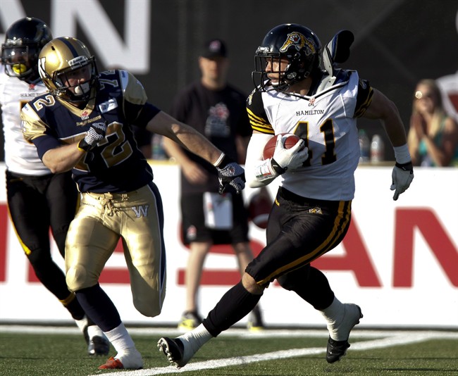 Hamilton Tiger-Cat Erik Harris, right, is chased by Winnipeg Blue Bombers receiver Brett Carter as he returns an interception during first quarter CFL pre-season action in Guelph, Ont., in June 2013. He stayed on the practice roster after dressing for a July game last season, but plans to fight for a spot on the team this year.