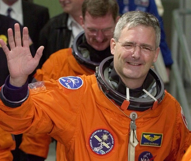 Mission specialist Marc Garneau of Canada waves to photographers as he leaves the Operations and Checkout Building on Thursday night, Nov. 30, 2000.
