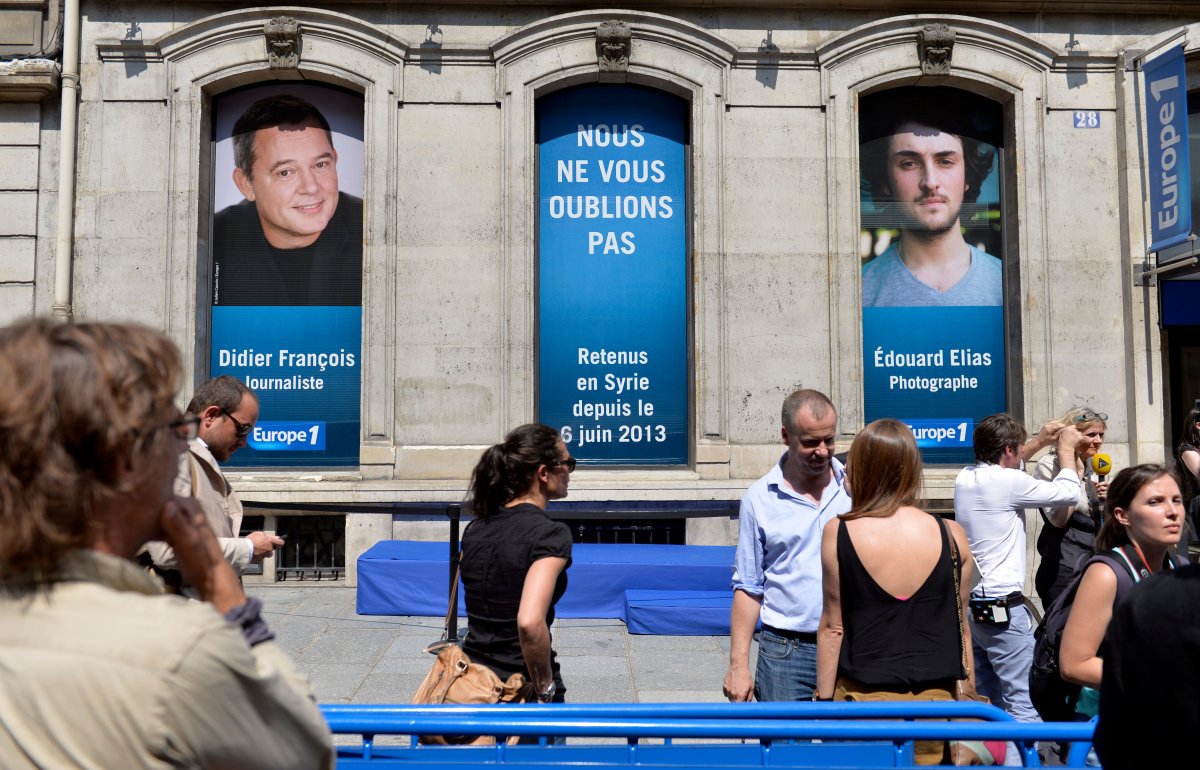Portraits of the two French radio journalists Didier Francois (L) and Edouard Elias kidnapped in Syria on June 6, 2013 are hung on the windows of Europe 1 radio station studio in Paris on July 9, 2013 as people take part in a rally in their support. 