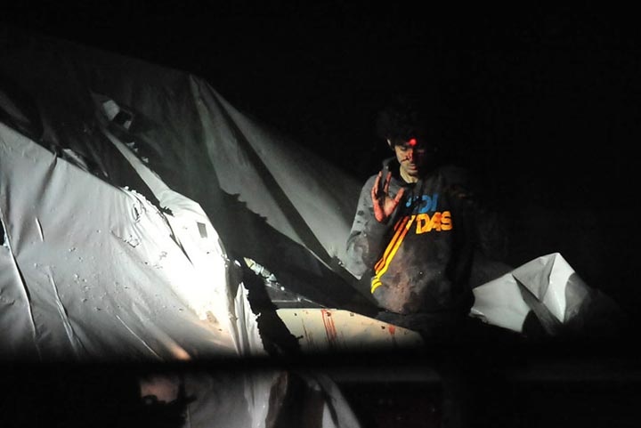 An injured Dzhokhar Tsarnaev emerges from the boat where he had been hiding on April 19, 2013. A red dot  from a sniper's rifle can be seen on his head. 