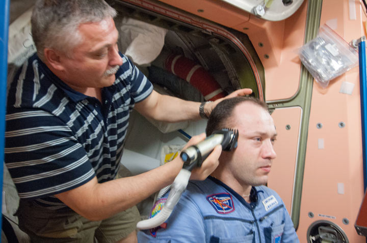 Russian cosmonaut Fyodor Yurchikhin, Expedition 36 flight engineer, trims the hair of Russian cosmonaut Alexander Misurkin, flight engineer, in the Unity node of the International Space Station. Yurchikhin used hair clippers fashioned with a vacuum device to garner freshly cut hair. (NASA)