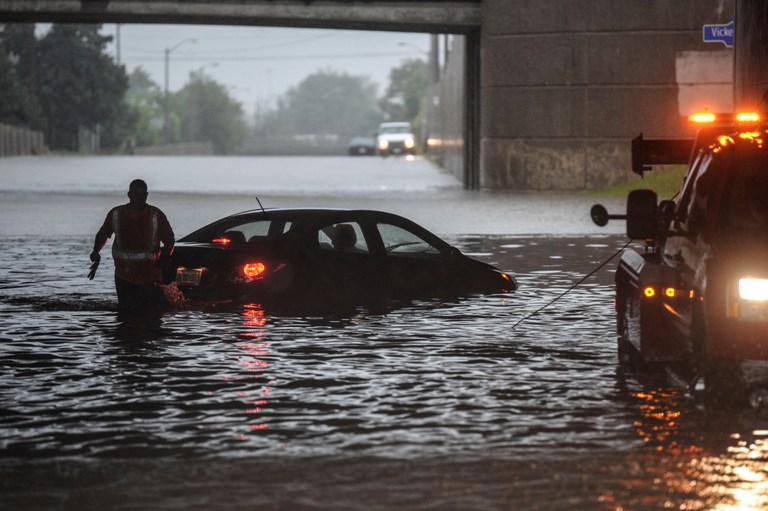 Joshua Hudson helps tow a stranded car out from a flooded underpass along the East Mall near Dundas Street West, Monday. (Canadian Press)