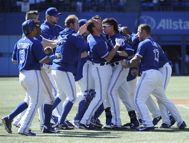 Toronto Blue Jays' Colby Rasmus (centre, sunglasses) is mobbed by teammates after driving in Emilio Bonifacio for the winning run with a single against the Houston Astros in the bottom of the ninth inning of their MLB baseball game on Sunday, July 28, 2013 in Toronto.