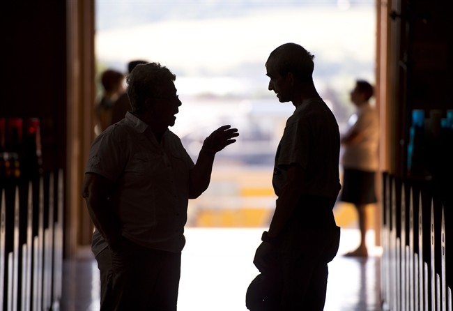 Pierrette Turgeon-Blanchet, left, is silhouetted inside the Sainte-Agnes church speaking to local resident Serge Rouillard, who was evacuated after the train crash blaze in Lac-Megantic, Que., Monday, July 15, 2013.