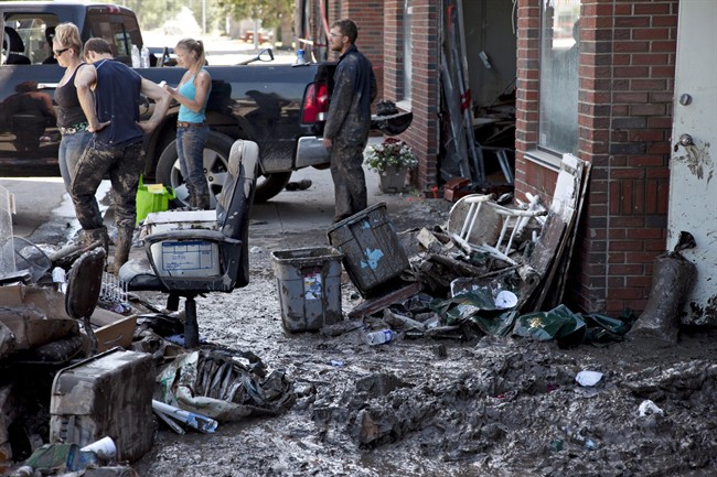 Mud and building contents litter the sidewalk as clean up work commences on downtown places of business in High River.