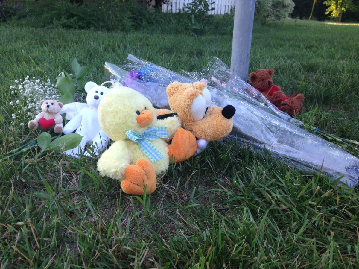 Flowers and stuffed animals lay outside the Westwood area home on Wednesday.
