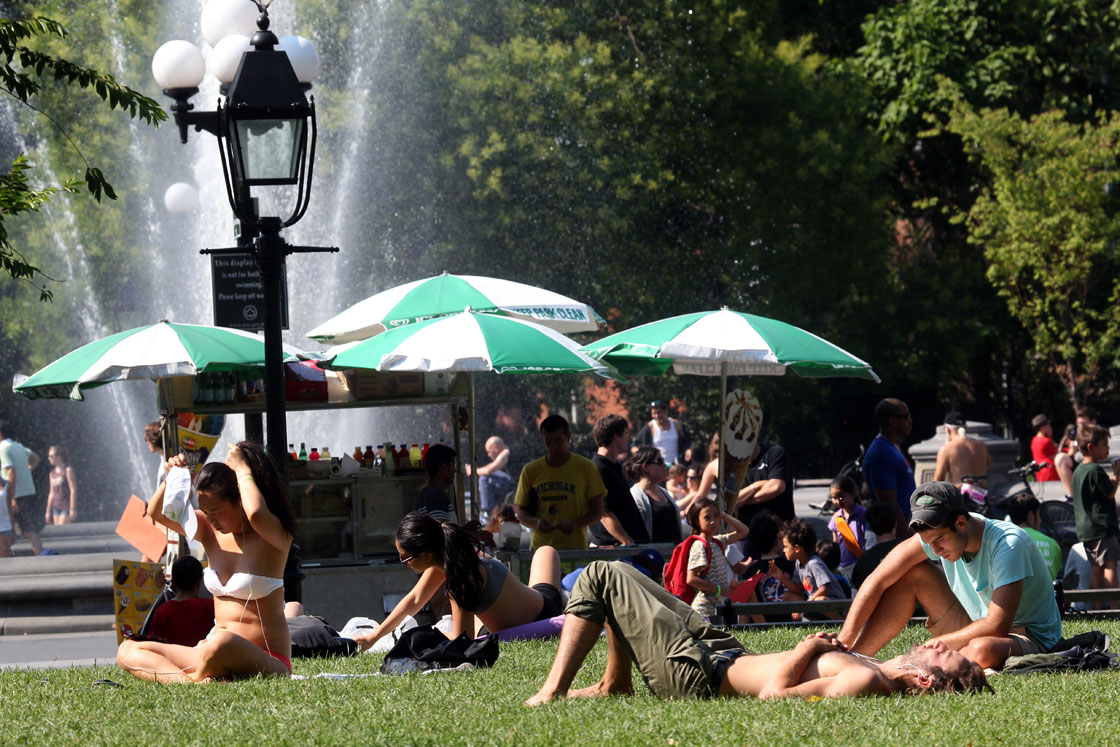 People take in the sun at Washington Square Park in New York City on July 16, 2013 as a heatwave descended on the city. 