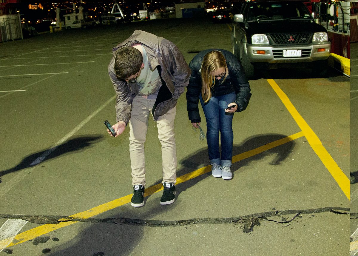 Students photograph a crack on the ground on the wharf on the waterfront after a 6.5 magnitude earthquake hit Wellington on July 21, 2013. A strong earthquake struck off New Zealand, jolting the nation's capital but no tsunami alert was issued and there were no immediate reports of damage.
