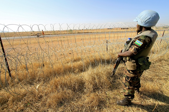 This file photo shows a Rwandan peacekeeper serving with the joint United Nations-African Mission in Darfur (UNAMID) stands guard in a field in Zalingei in western Darfur on December 1, 2010.