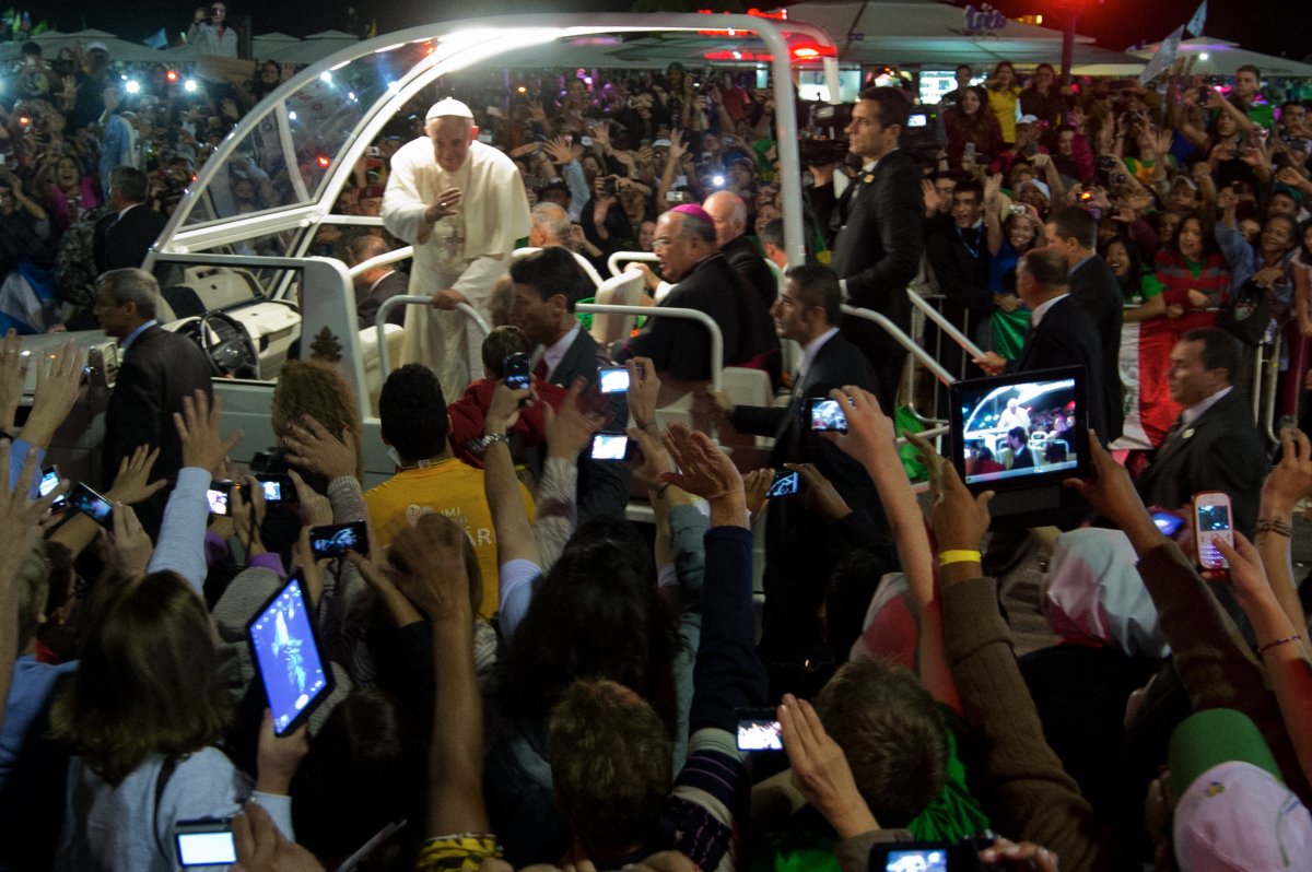Pope Francis waves at faithfuls standing along the beachfront in Rio de Janeiro on his way for a prayer vigil with hundreds of thousands of young Catholic pilgrims attending World Youth Day (WYD) at Copacabana beach on July 27, 2013, during his week-long visit to Brazil.