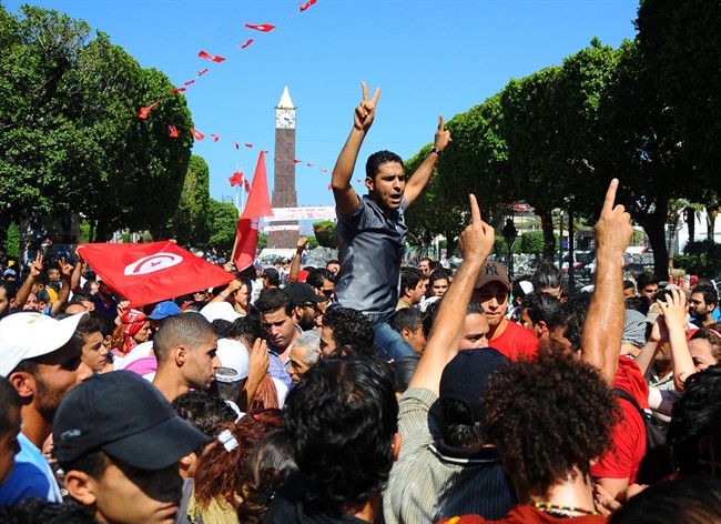 Protesters gather on the main avenue of Tunis after the leader of a leftist Tunisian opposition party, Mohammed Brahmi, was gunned down as he left home, in Tunisia, Thursday, July 25, 2013.