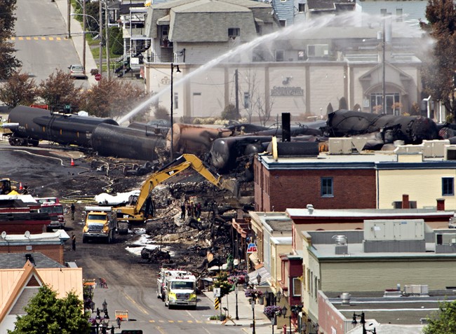 Searchers dig through the rubble for victims of the inferno in Lac-Megantic, Quebec, Monday, July 8, 2013, as firefighter continue to hose down tanker cars to prevent explosions. A runaway train derailed igniting tanker cars carrying crude oil early Saturday. 