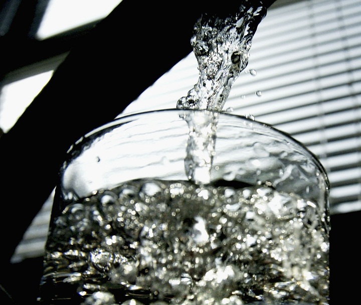 A glass is filled with water from the tap.