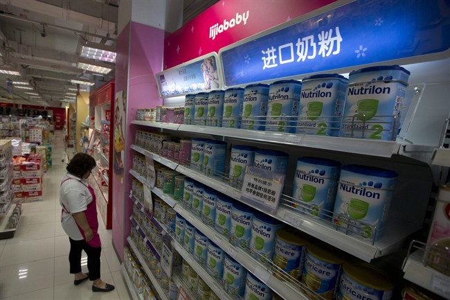 A salesperson walks by tins of baby formula with the Chinese characters "Imported Baby Formula" on the top of shelves in Beijing Thursday, July 4, 2013.