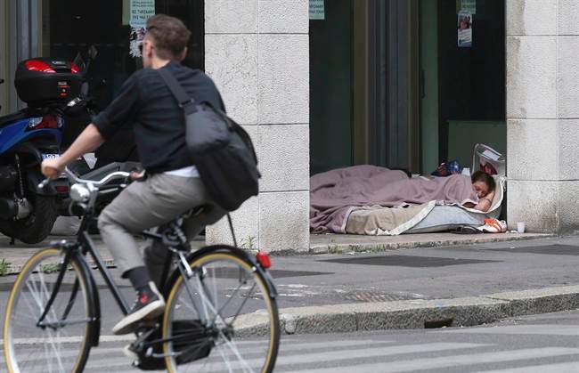 A young homeless sleeps under an arcade of a closed bank, in Milan, Italy, Thursday, June 27, 2013. 