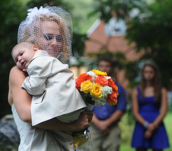 Christine Swidorsky carries her son and the couple's best man, Logan Stevenson, 2, down the aisle to her husband-to-be Sean Stevenson during the wedding ceremony on Saturday, Aug. 3, 2013 in Jeannette, Pa.