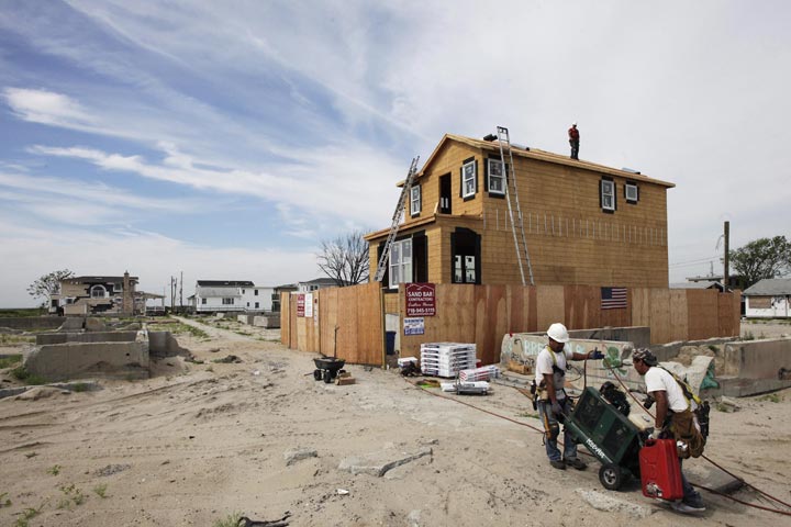 Workers haul equipment to a construction site in the Breezy Point community in New York's Queens borough on Wednesday, July 24, 2013. 