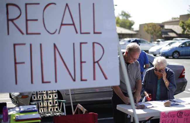 Greg Timms, left, signs a petition to recall San Diego Mayor Bob Filner, alongside Tana Piontek, right, at a stand set up in the parking lot of a shopping center Wednesday, Aug. 21, 2013, in San Diego.
