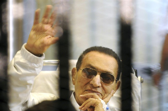 FILE - In this Saturday, April 13, 2013 file photo, former Egyptian President Hosni Mubarak waves to his supporters from behind bars as he attends a hearing in his retrial on appeal in Cairo, Egypt. Officials say an Egyptian court has ordered the release of ex-President Mubarak, but it’s not immediately clear whether the prosecutors will appeal the order. 