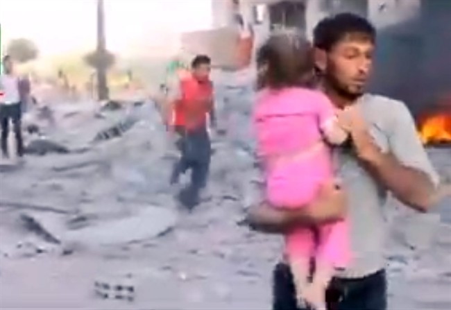 In this image taken from video obtained from the Shaam News Network, which has been authenticated based on its contents and other AP reporting, a Syrian man carries an injured child away from a missile strike in Raqqa, Syria, Wednesday, Aug. 7, 2013. Wednesday’s missile attack came after Human Rights Watch said missiles fired by the Syrian army into populated areas have killed hundreds of civilians in recent months. 