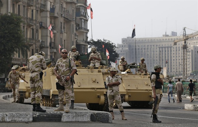 FILE - In this file photo taken Friday, Aug. 16, 2013, Egyptian army soldiers take their positions on top and next to their armored vehicles while guarding an entrance of Tahrir square, in Cairo, Egypt. Israel is carefully watching events in Egypt and keeping in touch with the Egyptian army through the Arab nation's latest turmoil, officials say, working together in the common battle against Islamic militants. 