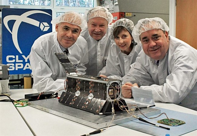 Officials in Glasgow, Scotland, pose in this recent photo with a satellite that will carry artwork created by Los Angeles artists Jon Gibson and Amanda White, not shown, in British company Clyde Space facility in Glasgow. 