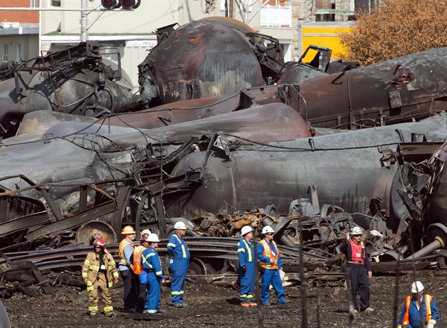 Workers stand before mangled tanker cars at the crash site of a train derailment and fire in Lac-Megantic, Quebec, in this July 16 file photo. 