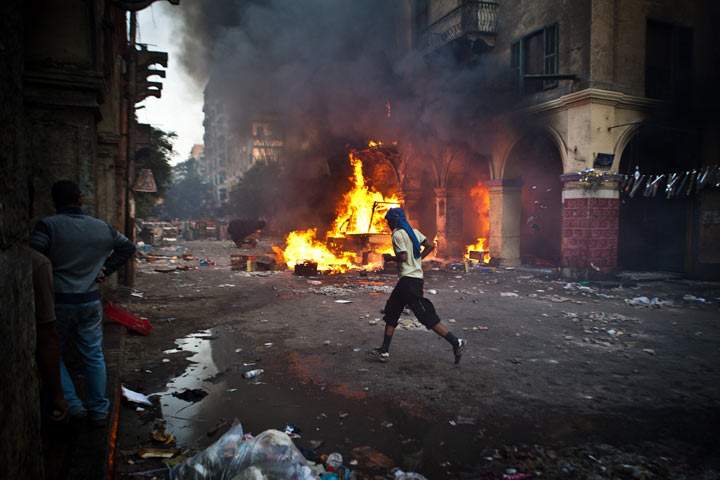 A supporter of the Muslim Brotherhood and of ousted president Mohamed Morsi runs past a burning vehicle during clashes with security officers close to Cairo's Ramses Square, on August 16, 2013. (VIRGINIE NGUYEN HOANG/AFP/Getty Images).