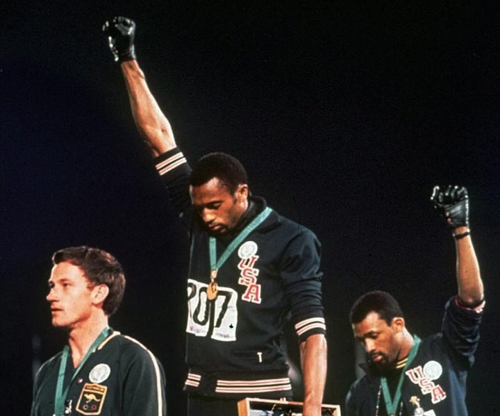United States gold medalist Tommie Smith, center, and bronze medalist John Carlos, right, stare downward while extending their gloved hands skyward in racial protest alongside Australian silver medalist Peter Norman during the playing of "The Star Spangled Banner" following the 200-meter race at the Mexico City Summer Olympics, Oct. 16, 1968. 
