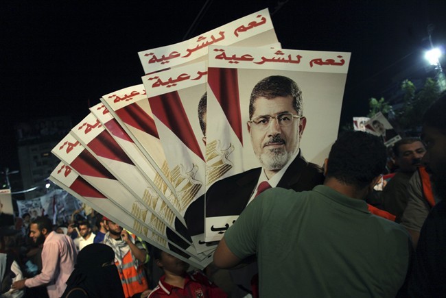 A supporter of Egypt's ousted President Mohammed Morsi holds his posters with Arabic writing which reads " Yes for legality," during a protest outside Rabaah al-Adawiya mosque, where protesters have installed a camp and hold daily rallies at Nasr City in Cairo, Egypt, Tuesday, Aug. 6, 2013.