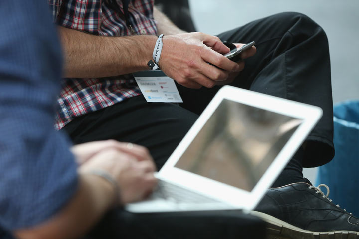 Participants work on a smartphone and laptop computer in between conferences on the first day of the re:publica 2013 conferences on May 6, 2013 in Berlin, Germany.