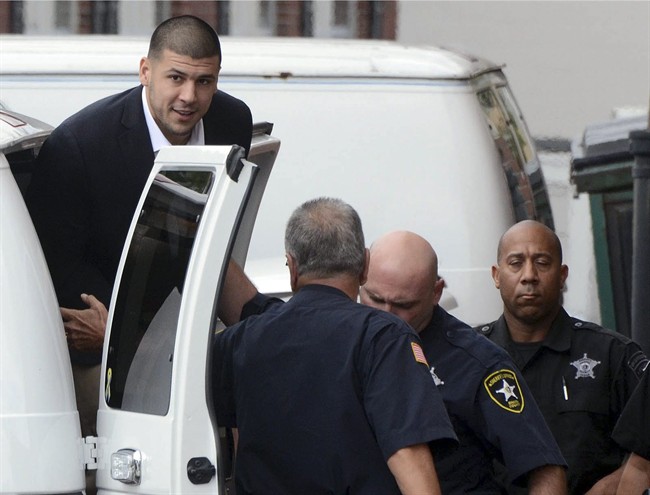 Former New England Patriots football player Aaron Hernandez, top left, is escorted out of a van as he arrives at district court for a brief hearing Friday, Aug. 30, 2013, at Attleboro, Mass. 