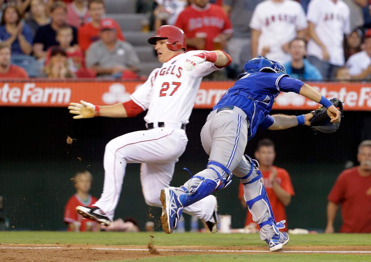 Toronto Blue Jays catcher J.P. Arencibia chases a wide throw to home as Los Angeles Angels Mike Trout scores, with two more runs scoring on Arencibia's throwing error to second, trying to get Howie Kendrick, in the fifth inning of a baseball game in Anaheim, Calif., Saturday, Aug. 3, 2013. 