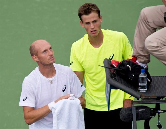Nikolay Davydenko, of Russia, advises the umpire of his withdrawal from the game due to injury as Canada's Vasek Pospisil looks on during quarter final play at the Rogers Cup tennis tournament Friday August 9, 2013 in Montreal. THE CANADIAN PRESS/Paul Chiasson.