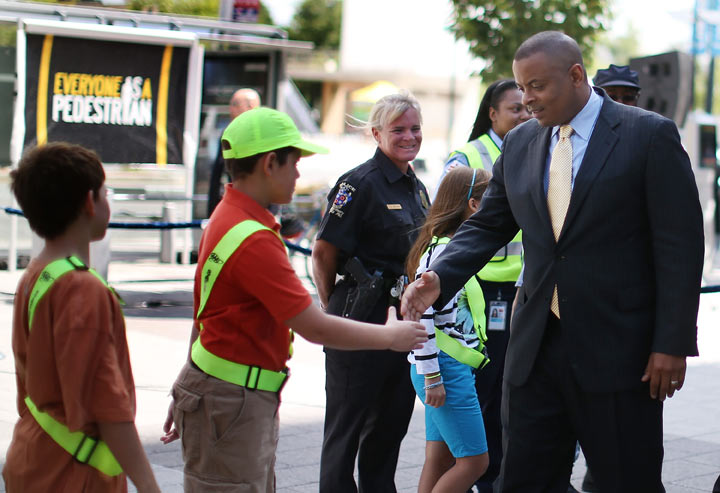 Transportation Secretary Anthony Foxx (R) greets school children after announcing new federal pedestrian safety initiative during a news conference at the Department of Transportation, August 5, 2013 in Washington, DC.