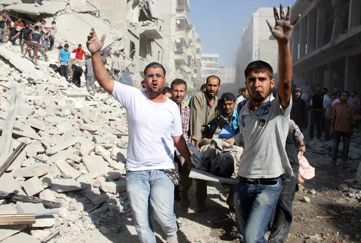Syrian men evacuate a victim following an air strike by regime forces in the northern city of Aleppo on August 26, 2013.