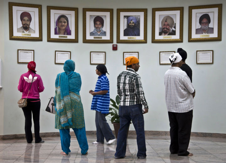 Visitors look at a memorial near the entrance of the Sikh Temple of Wisconsin Wednesday, July 31, 2013, in Oak Creek, Wis. Twelve months ago a white supremacist shot and killed six temple members, and the survivors plan to mark the one-year anniversary with solemn religious rites and a candlelight vigil. 