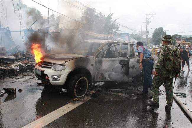 Police and military personnel inspect a burnt vehicle after a powerful bomb exploded in Cotabato city, southern Philippines on Monday Aug. 5, 2013. 