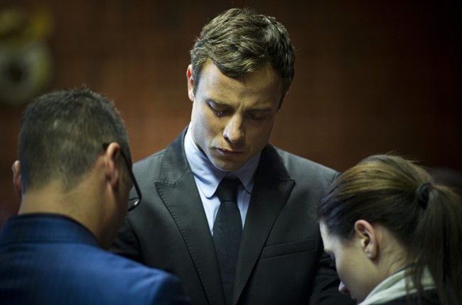 Oscar Pistorius cries as he prays with his sister Aimee and brother Carl in the magistrates court in Pretoria, South Africa, Monday, Aug. 19, 2013. 