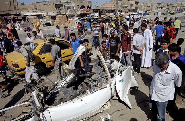 In this Monday, July 29, 2013, file photo, Iraqis inspect the aftermath of a car bomb attack, in the Shiite enclave of Sadr City, Baghdad, Iraq. 