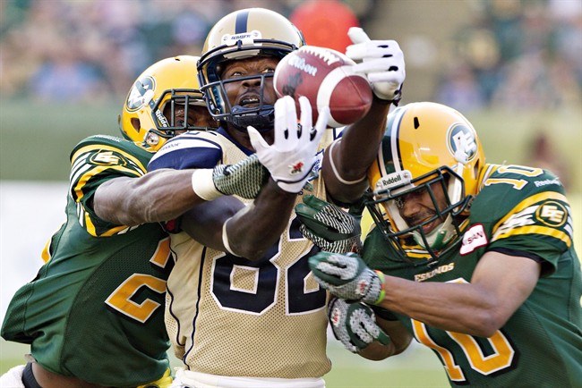 The Bombers' Terrence Edwards (centre) misses the catch as Edmonton Eskimos' Marcell Young (left) and Donovan Alexander (right) defend on Sept. 14.