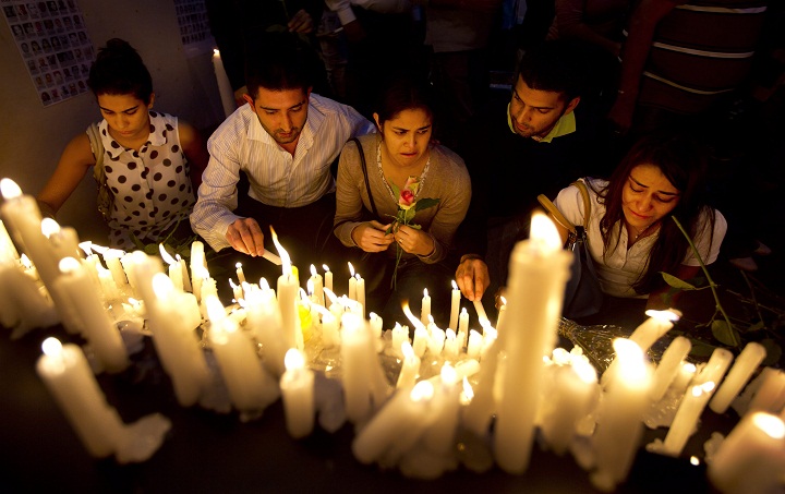 Foreigners lay flowers and light candles to pay their respects as they and Kenyans came together to mark one week since the terrorist attack that killed 67 people, in front of the Westgate Mall in Nairobi, Kenya Saturday, Sept. 28, 2013.