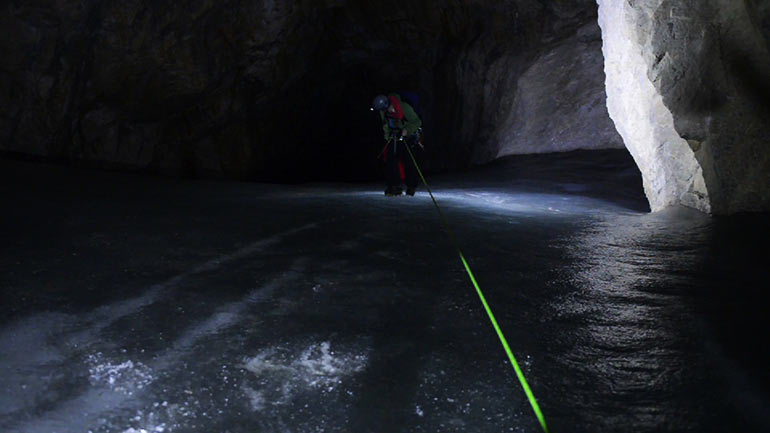 Caver Kate Graham rappels down the ice chute into Booming Ice Chasm
