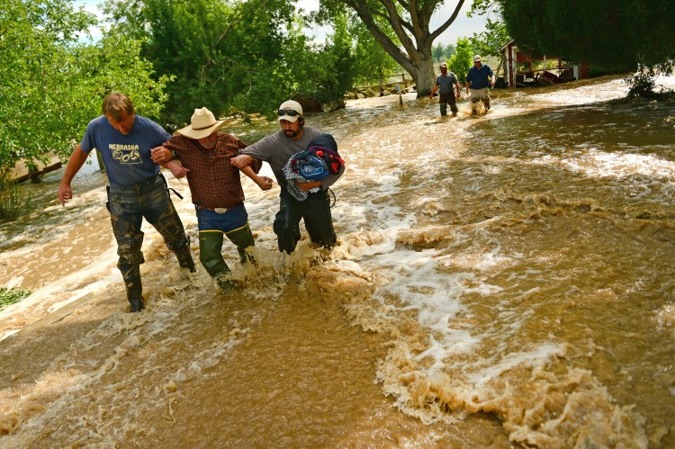 Local residents help a homeowner Dan Hull out of the flood waters that have consumed his house along Hygiene Road east of North 61st street and west of Hygiene, CO on September 14, 2013. They helped him go back into his house to rescue his cats. Massive flooding continues in 14 continues in Colorado. (Helen H. Richardson/ The Denver Post)