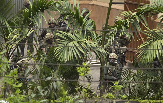 Kenyan soldiers walk around the side of the Westgate Mall as large explosions and heavy gunfire are heard in Nairobi, Kenya Monday, Sept. 23, 2013.