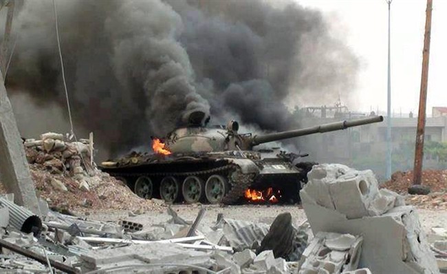 A Syrian military tank on fire during clashes with Free Syrian army fighters in Joubar, a suburb of Damascus, Syria, Wednesday, Sept. 18, 2013.
