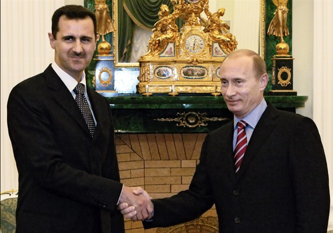 In this Dec. 19, 2006 file photo, Vladimir Putin, Russian president, right, and his Syrian counterpart Bashar Assad smile as they shake hands in Moscow's Kremlin.